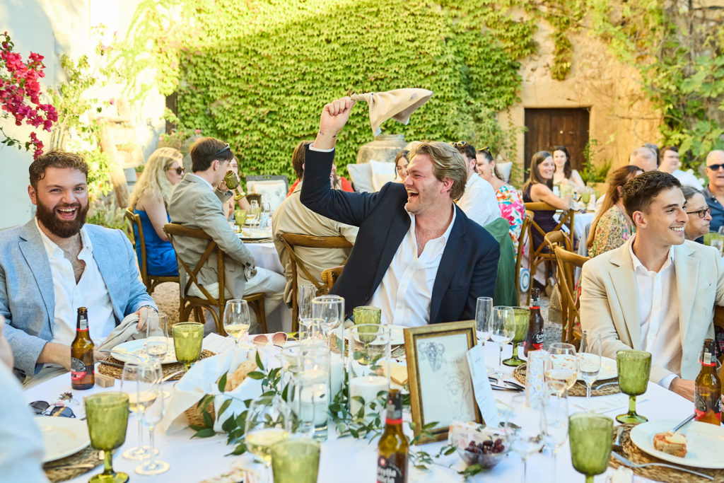 Wedding guests waving their napkins at the tables in the courtyard