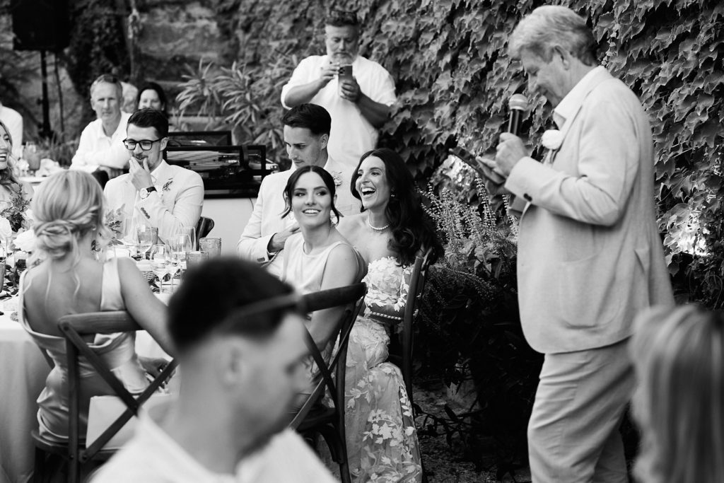Black and white photo of guests laughing during a speech