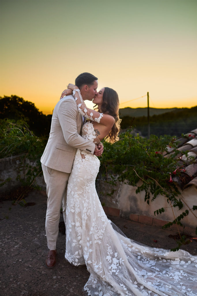 Bride and groom kissing at sunset with her lace train spread out at Son Boronat