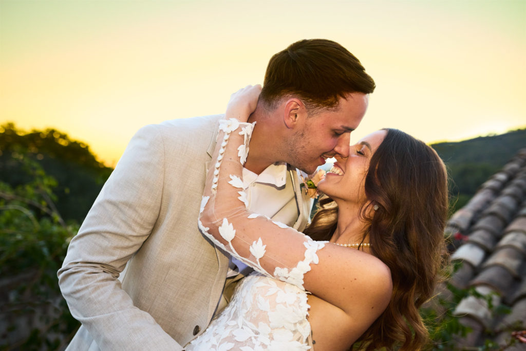 Bride and groom kissing at sunset over the rooftops of Son Boronat