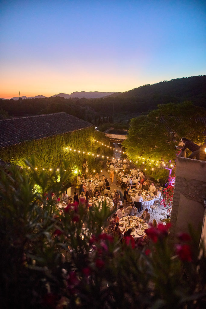 Wedding dinner lit by festoon lights in the courtyard at Son Boronat at dusk