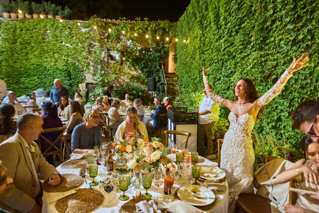 Bride cheering with her arms in the air during the wedding dinner