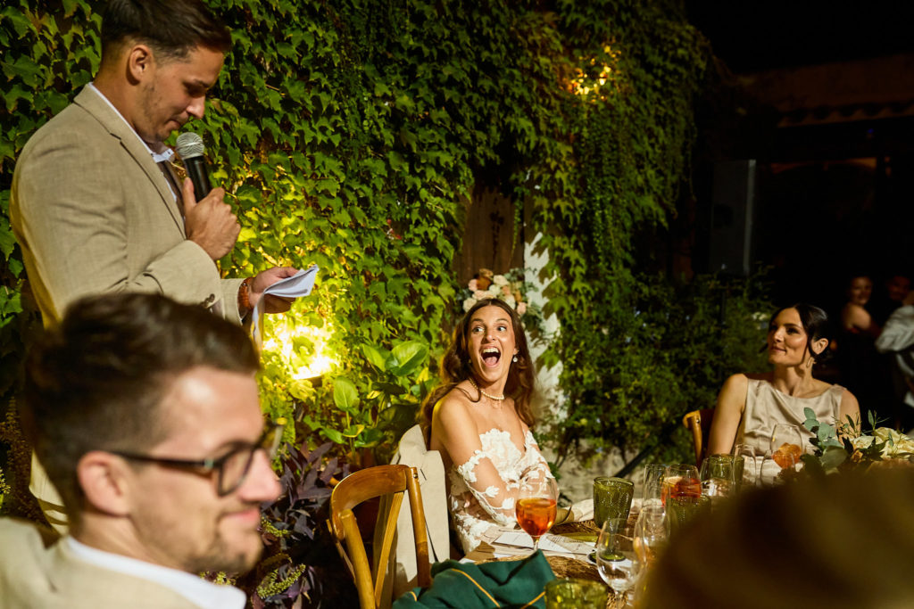 Bride laughing as the groom gives his speech