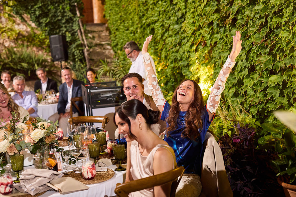 Wedding guests cheering at the table with their arms in the air