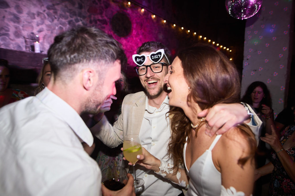 Bride and groom in novelty sunglasses kissing on the dance floor