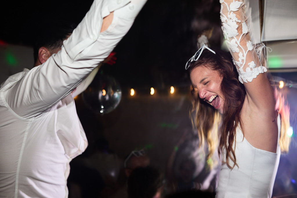 Bride laughing as she is lifted above the crowd on the dance floor