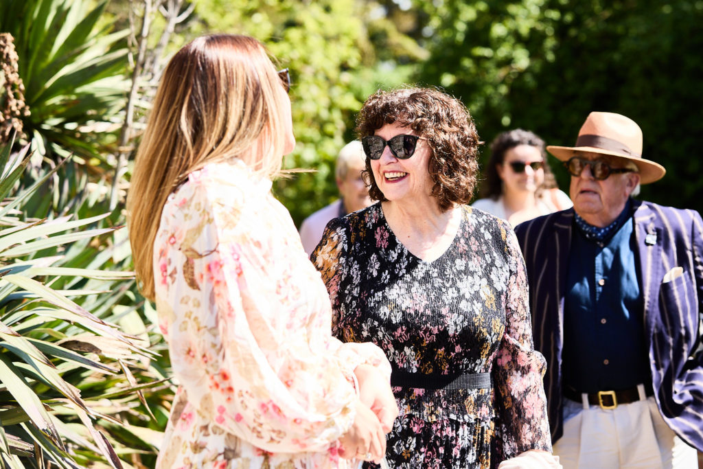 Wedding guests chatting in the sunshine before the ceremony