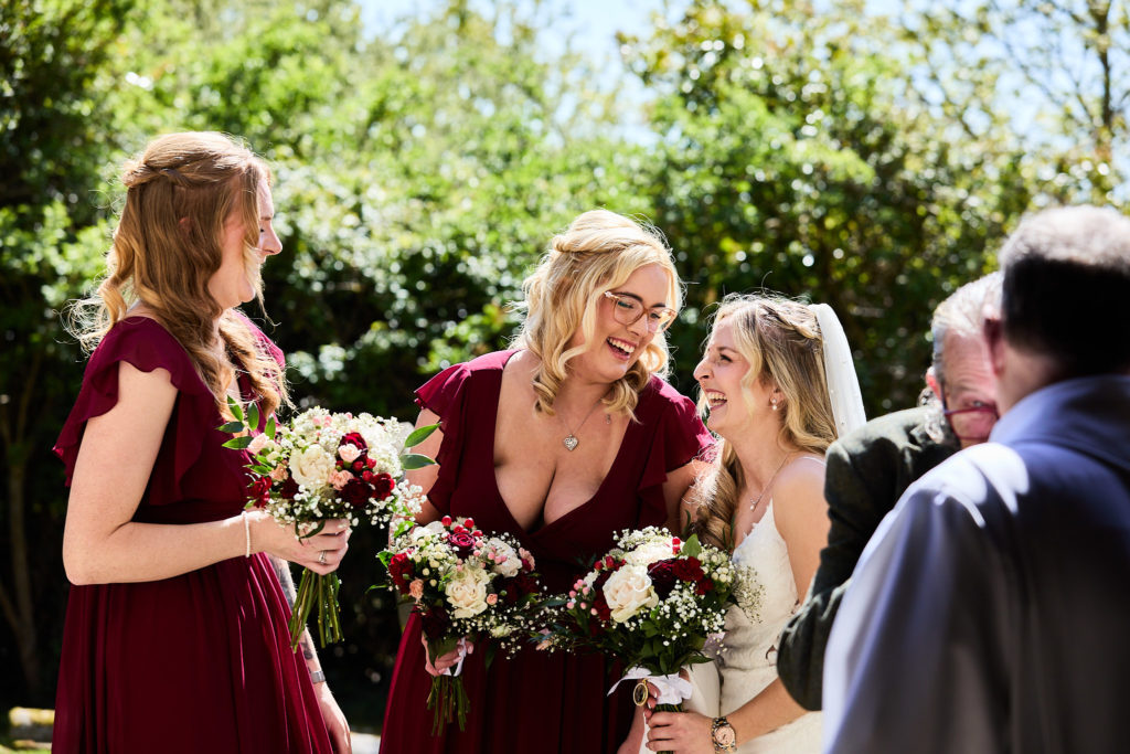 Bride and bridesmaids with bouquets gathering outside the church