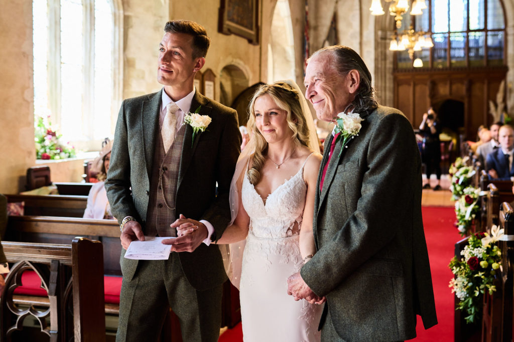 Bride arriving at the altar on the arm of an older man, with the groom beside her