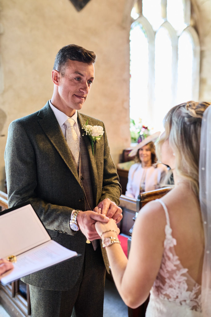 Groom placing the wedding ring on the bride's finger in church