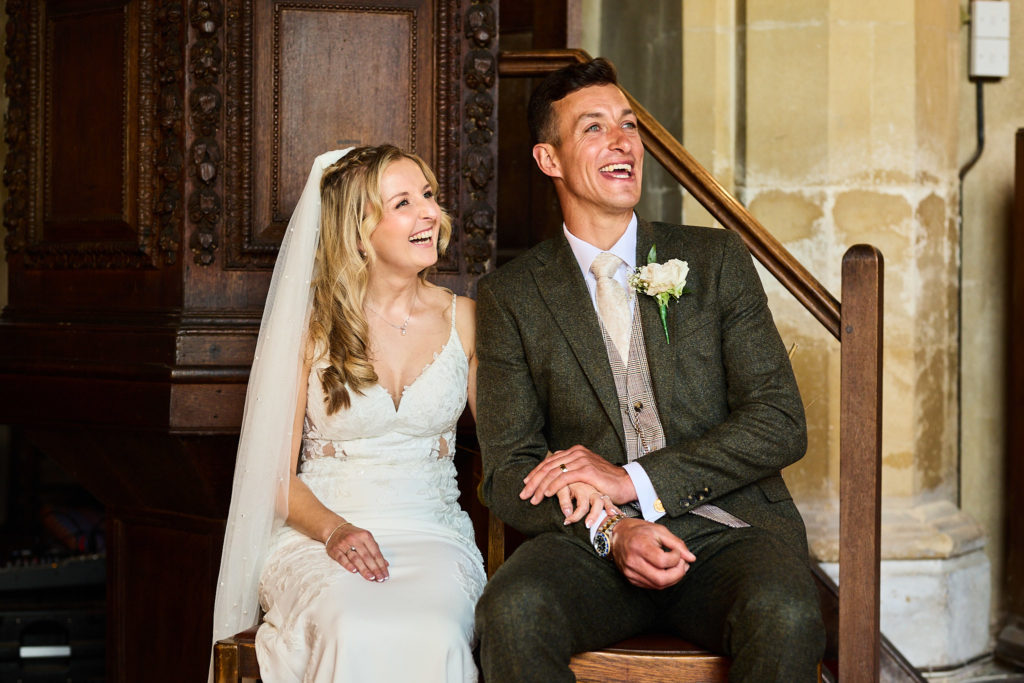 Bride and groom laughing as they sit together in church