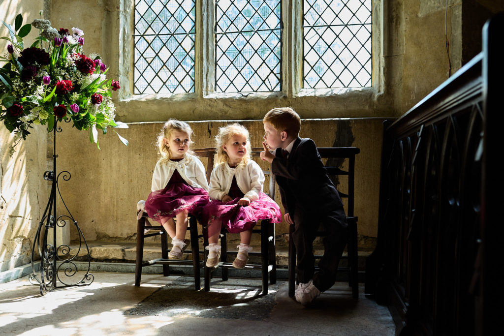 Flower girls and a page boy sitting under a church window