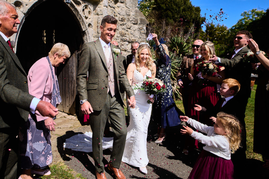 Bride and groom leaving the church as guests throw confetti