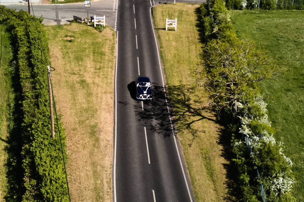 Aerial drone photo of the wedding car driving along a country lane
