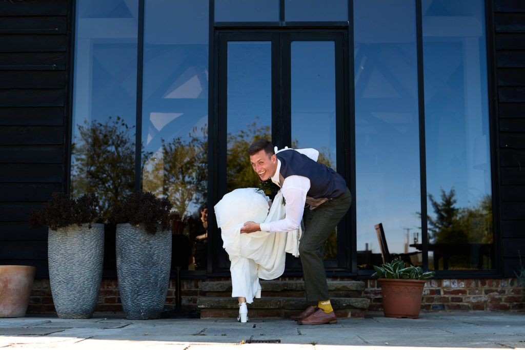 Groom dipping the bride in front of a black barn with glass doors