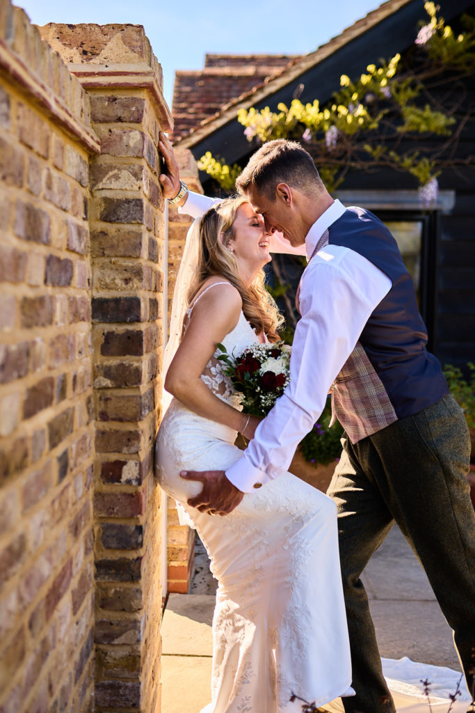 Bride and groom kissing against a brick wall