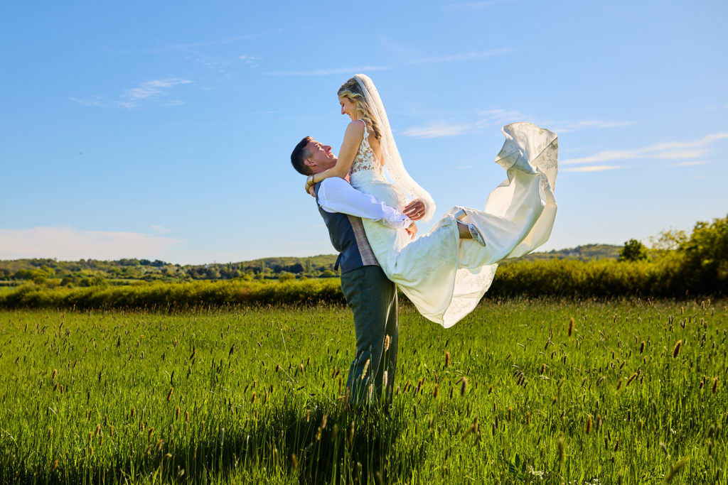 Groom lifting the bride and spinning her round in a field