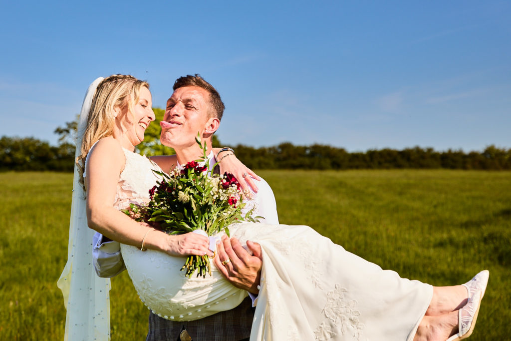 Groom carrying the bride in his arms as they laugh