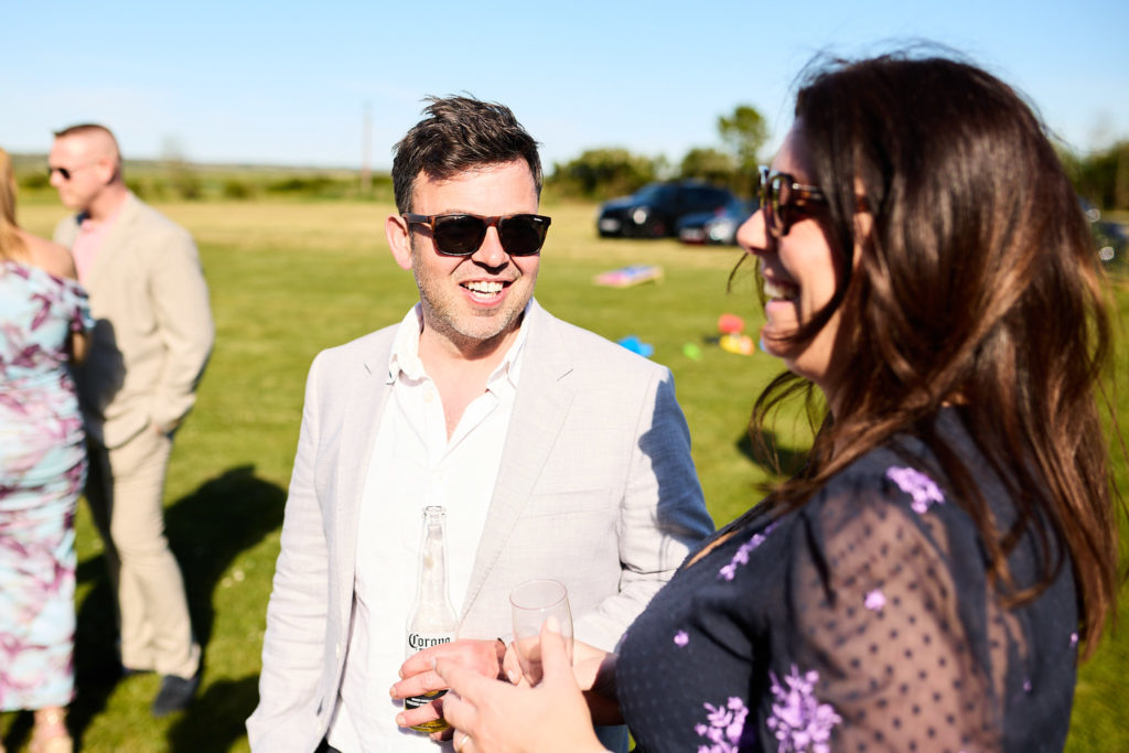 Wedding guests in sunglasses chatting on the grass