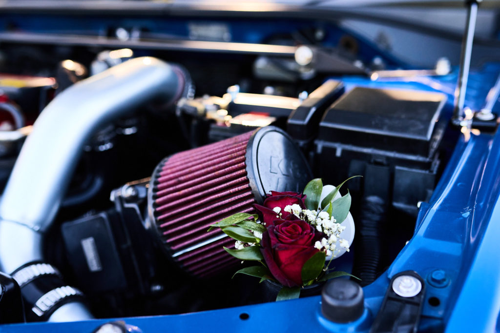 Red rose buttonhole tucked into a car engine bay