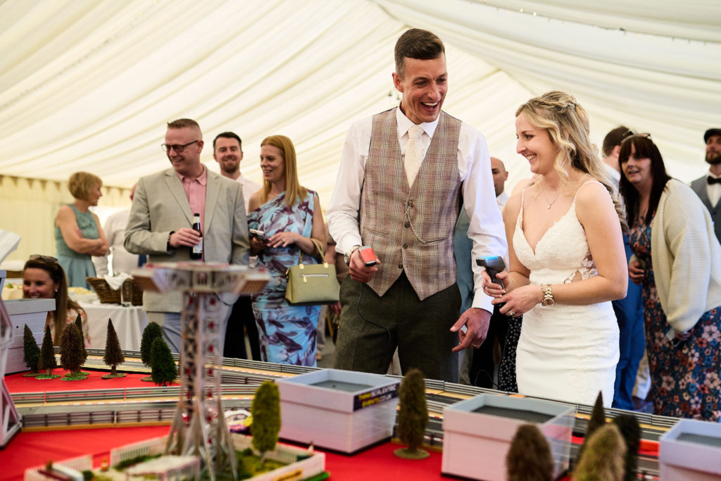 Bride and groom racing Scalextric cars in the marquee as guests watch