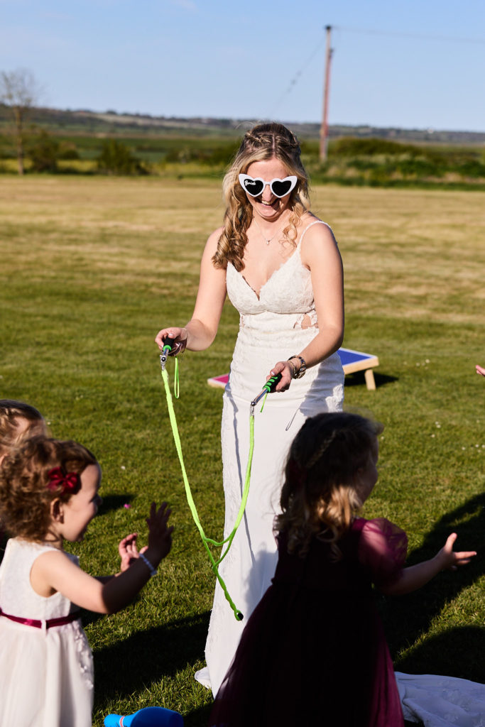 Bride in novelty sunglasses playing lawn games with children