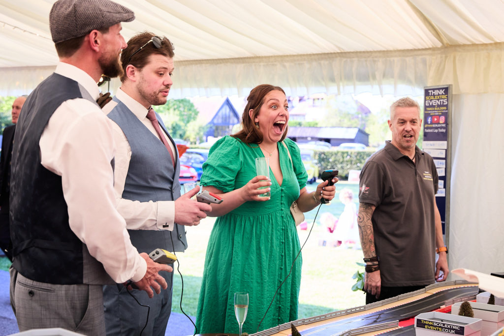 Wedding guests cheering as they race Scalextric cars in the marquee