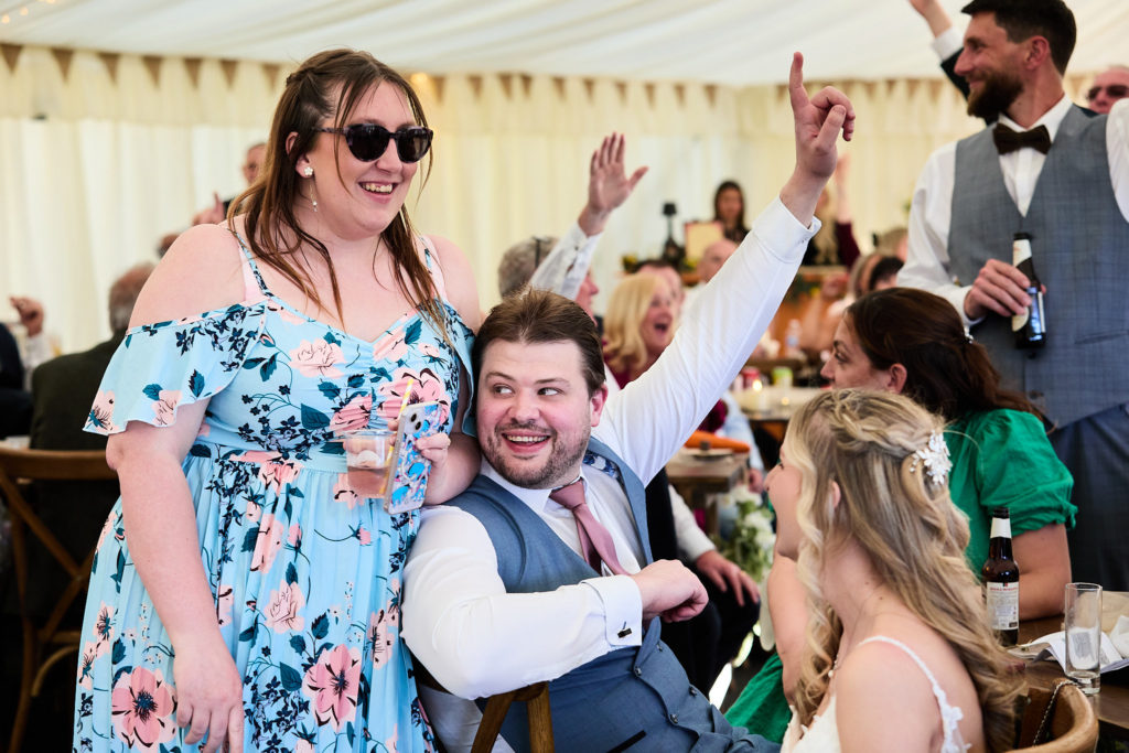 Wedding guests cheering at their table in the marquee
