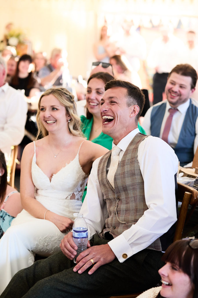 Bride and groom laughing during the wedding speeches
