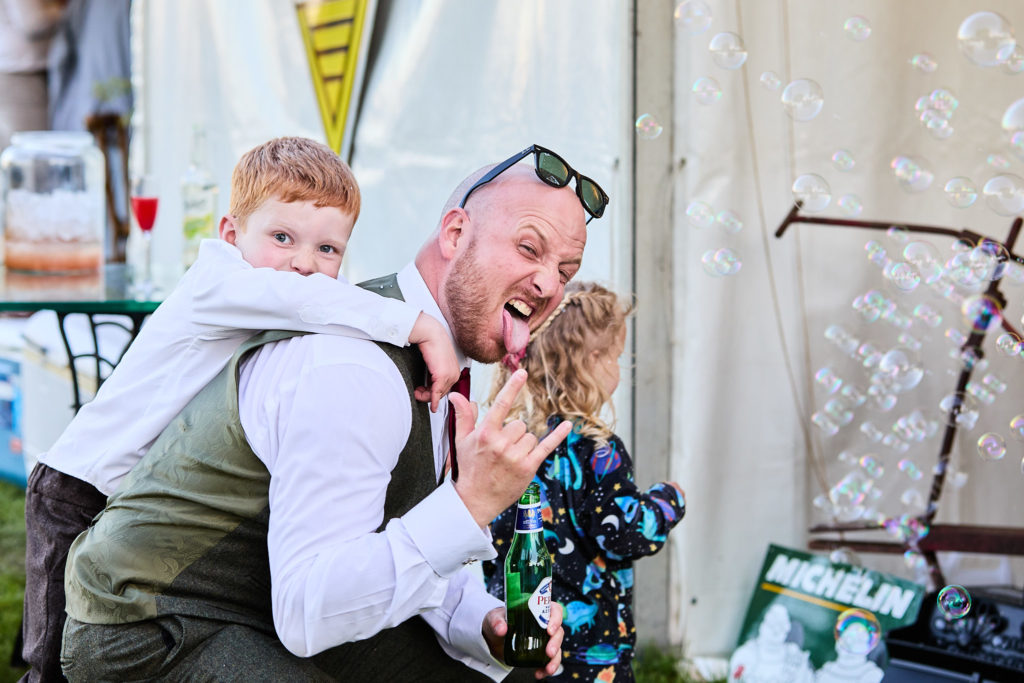 Man laughing as a boy climbs on his back among bubbles