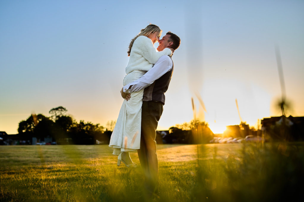 Bride and groom embracing in silhouette against the sunset