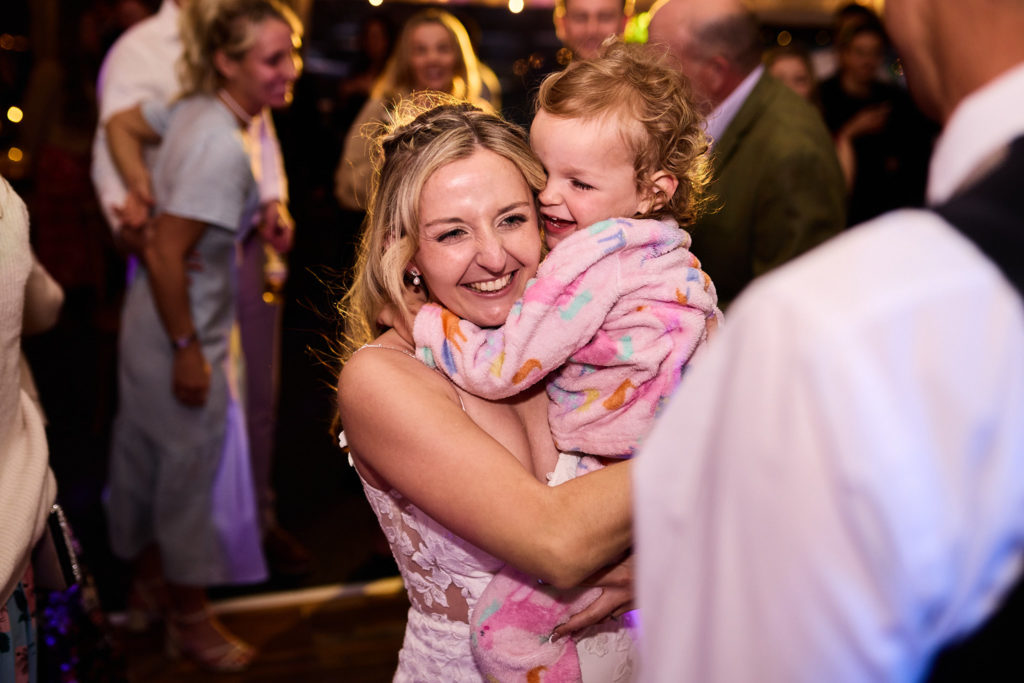 Bride cuddling a toddler on the dance floor