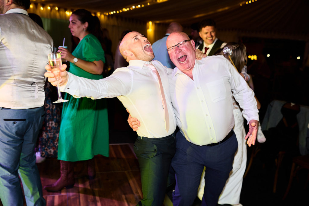 Two men singing arm in arm on the dance floor
