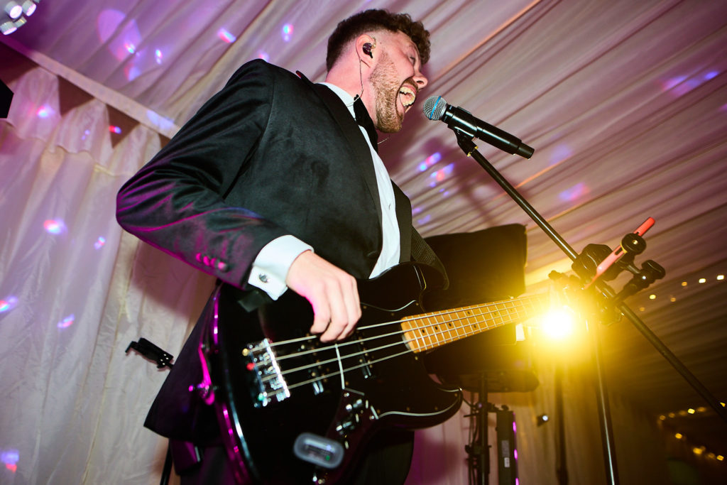 Bass guitarist performing under purple stage lights