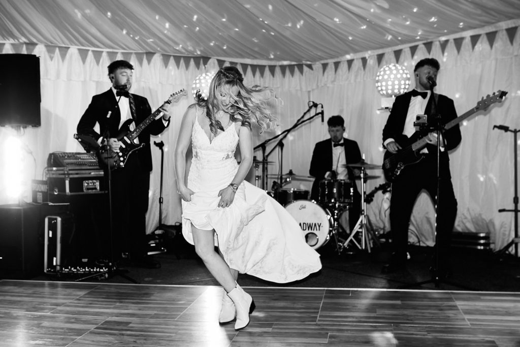 Black and white photo of the bride dancing in front of the band