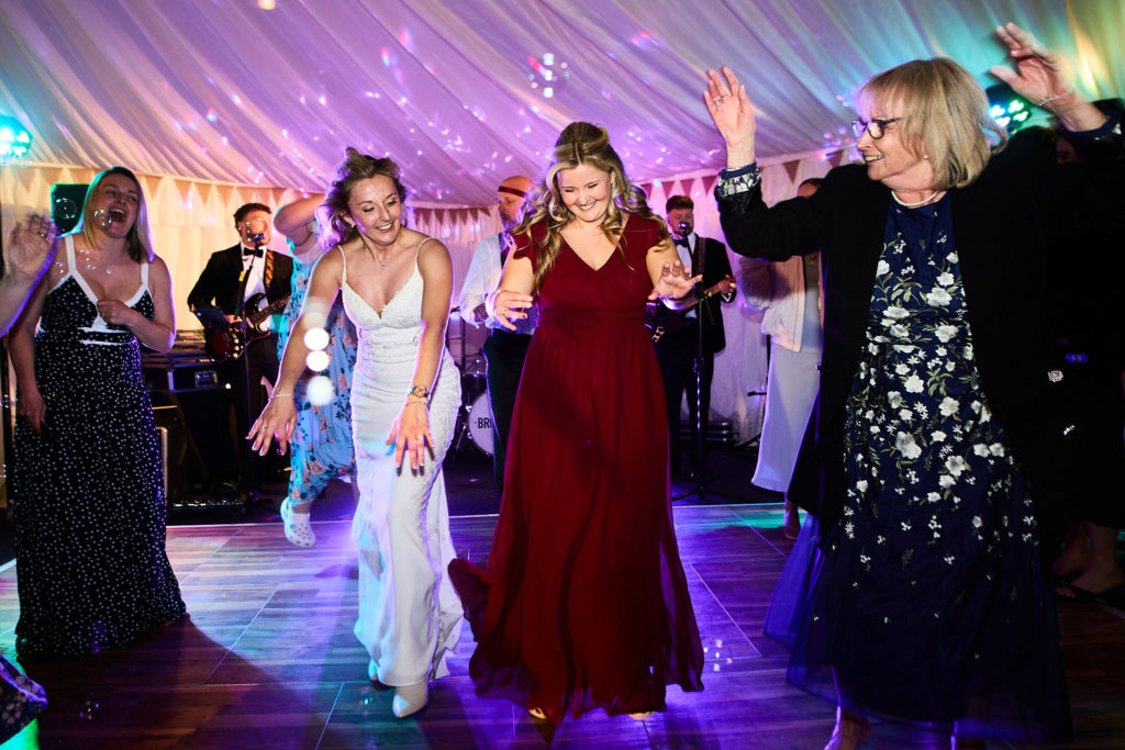 Bride dancing with a bridesmaid and guests under colourful lights