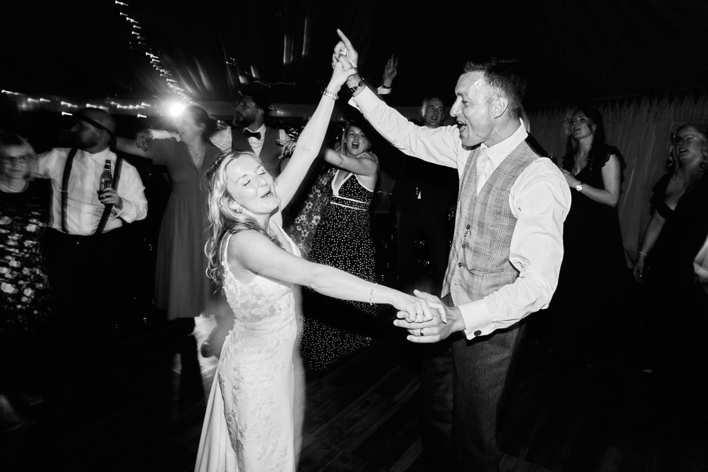 Black and white photo of the groom spinning the bride on the dance floor