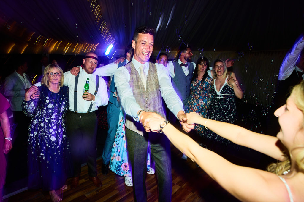 Groom dancing in a circle holding hands with guests