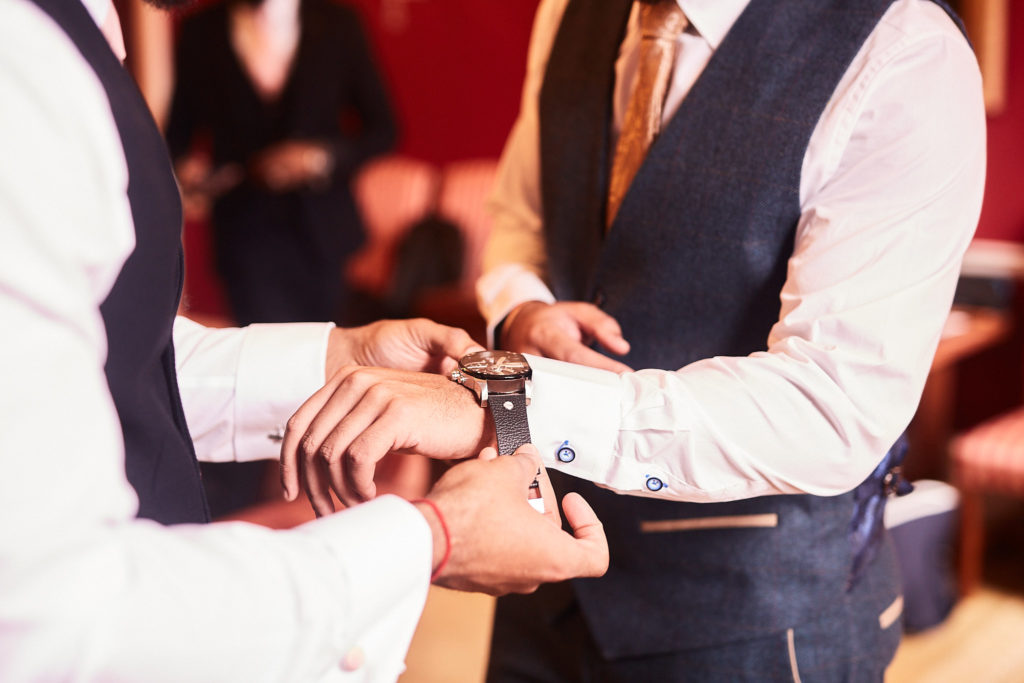 Close-up of a groomsman fastening the groom's watch