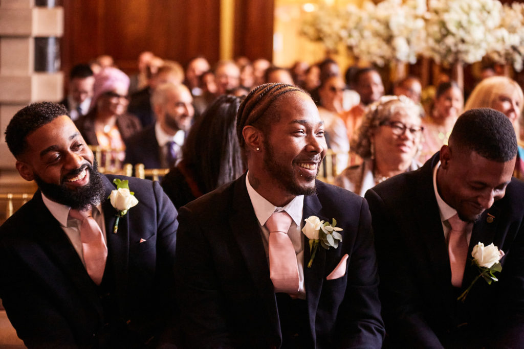 Groom and groomsmen laughing as they wait at the front of the ceremony