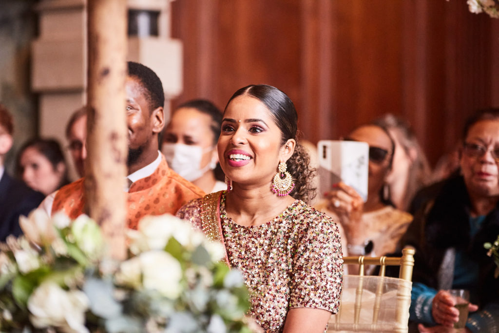 Wedding guest in a sequinned outfit smiling during the ceremony