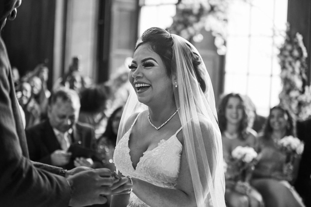 Black and white photo of the bride laughing during the exchange of rings