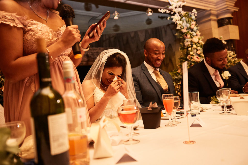 Bride in a sari laughing at the top table during the reception