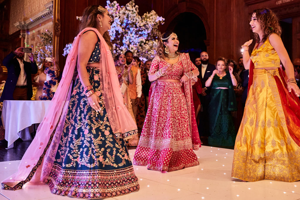 Bridesmaids in blue, pink and yellow lehengas dancing on the dance floor