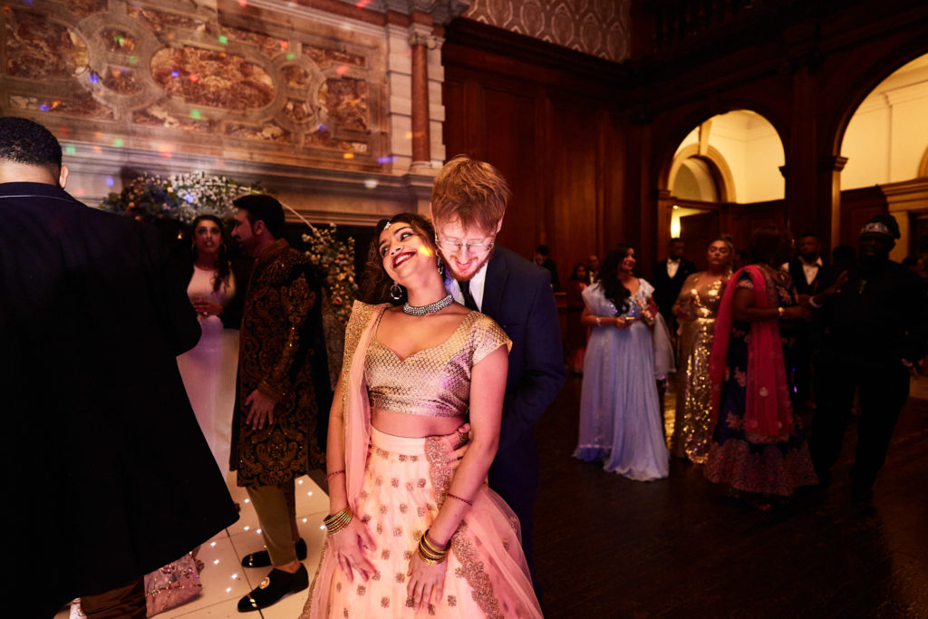 Bride in a pink lehenga laughing with guests at the evening reception