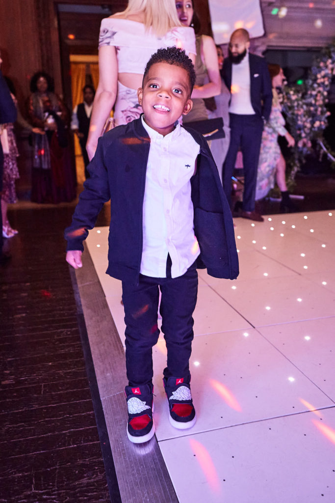 Young boy in a navy blazer and trainers dancing on the light-up dance floor