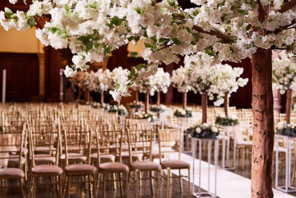 Ceremony room filled with white blossom trees at Addington Palace
