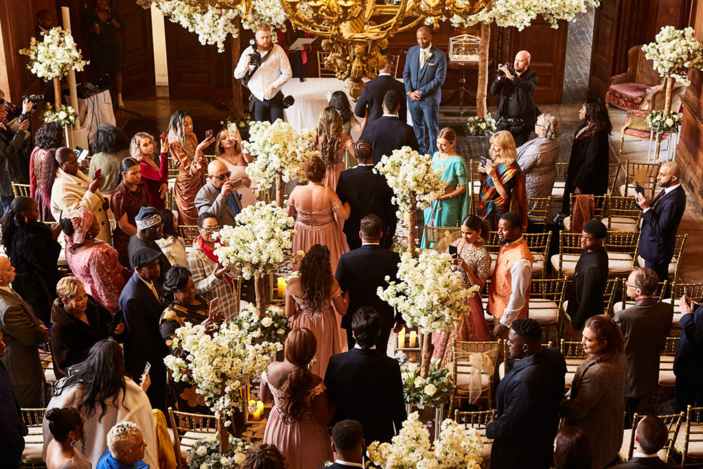 Wedding guests taking their seats among blossom trees, seen from above