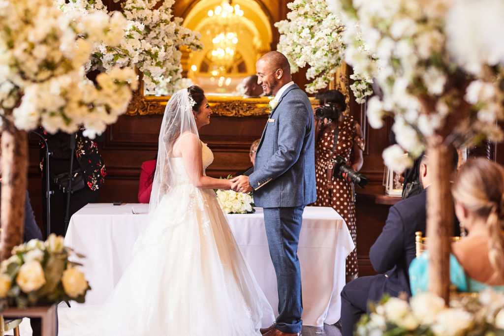 Bride and groom facing each other during their vows beneath white blossom trees