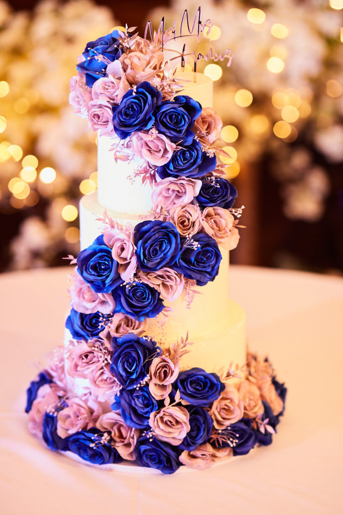 Tall wedding cake with a cascade of blue and pink roses
